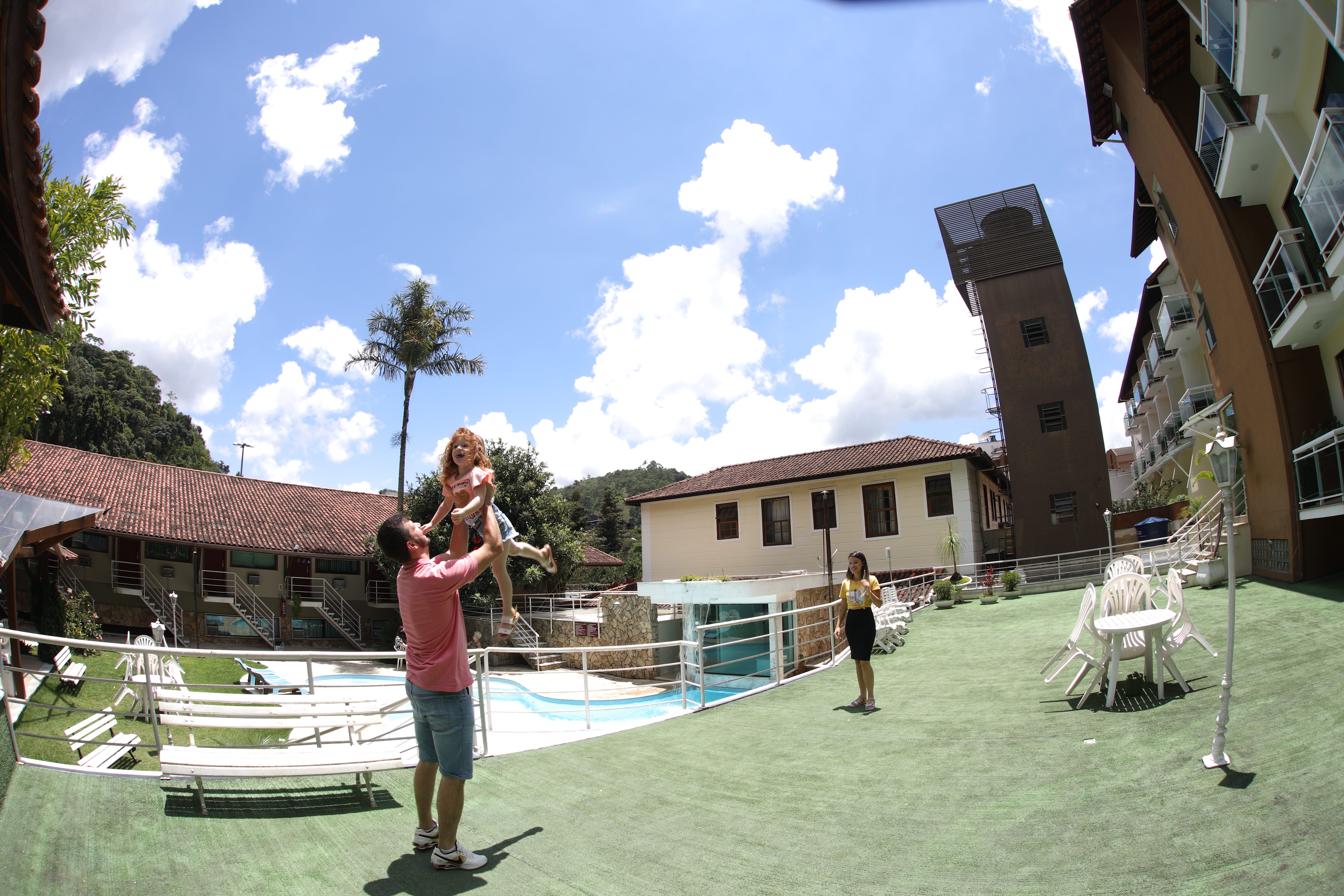 Pai brincando com a filha ao lado da piscina do Hotel Dominguez Plaza