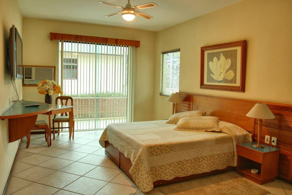Suíte do Hotel Dominguez Plaza com cama de casal e varanda